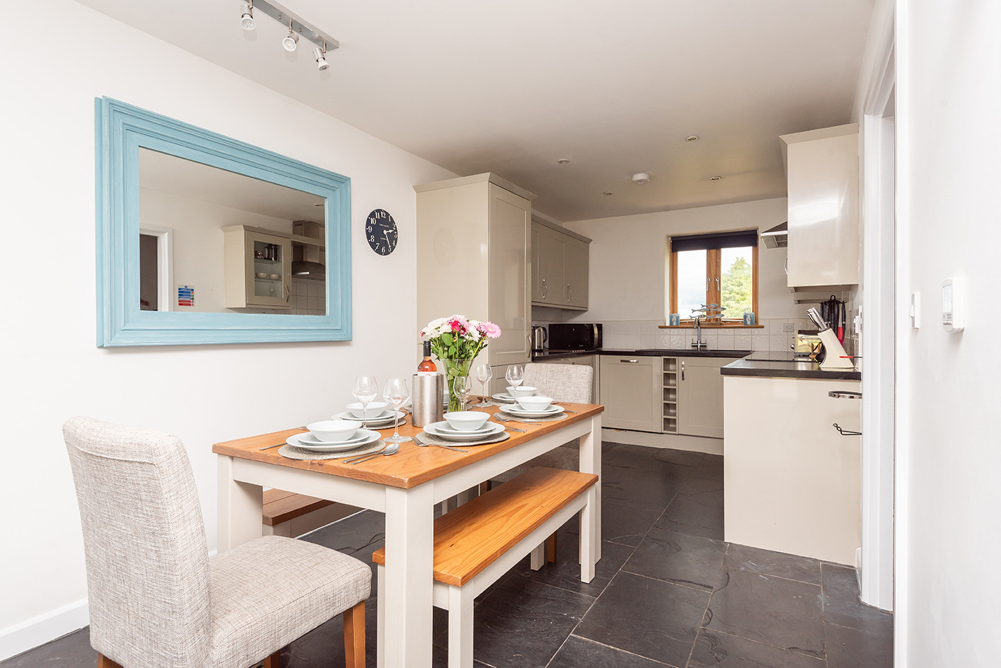 Open plan dining area with table, bench seats and dining chairs