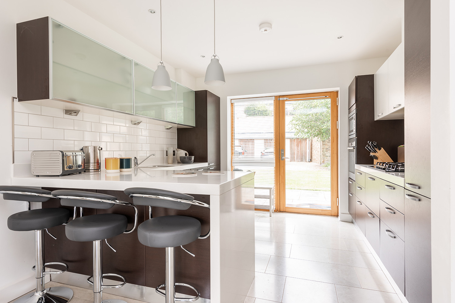 Fully integrated kitchen with breakfast bar and doors leading to private patio area.