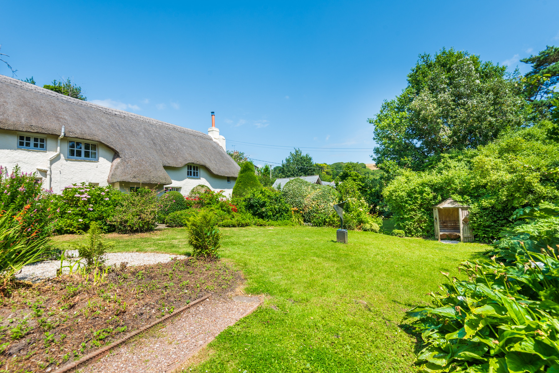 Sweeping mature gardens at this dog friendly thatched holiday cottage in South Devon