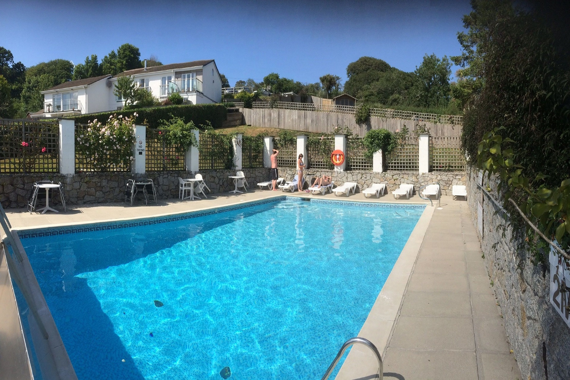 The heated swimming pool, with sun loungers and patio tables is accessed through the garden gate.